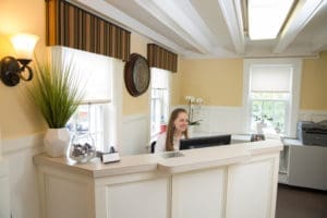 A girl sitting at the front desk of a dental office, ready to greet patients with a welcoming smile.
